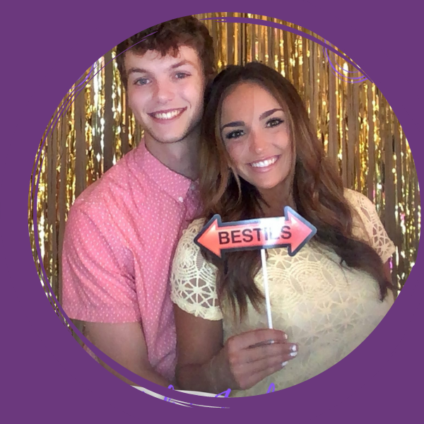 couple posing in a photo booth holding a sign 